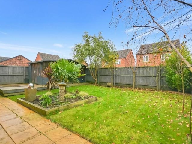 At the back of the house is this west-facing, landscaped garden with patio areas, a nice lawn, a central flowerbed and a pleasant selection of established shrubs.