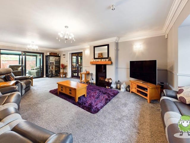 Here is the large living room at the Riverside Way property. It oozes luxury, with a feature fireplace and log burner adding warmth and character. In the background, sliding doors give access to the kitchen/living area.