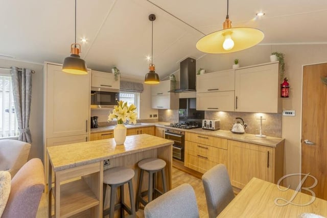 At the heart of the kitchen is a wooden breakfast bar island, with seating.
