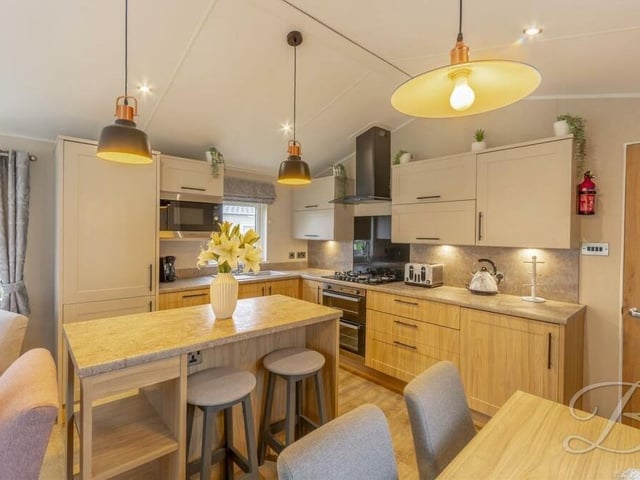 At the heart of the kitchen is a wooden breakfast bar island, with seating.