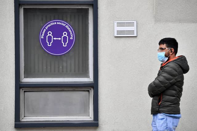 A customer wearing PPE stands near a sign asking people to socially distance as they queue to enter a NatWest bank (Photo by BEN STANSALL/AFP via Getty Images)