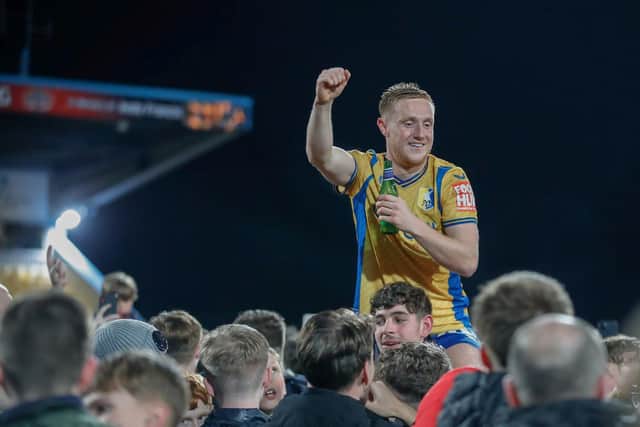 Mansfield Town players and fans celebrate promotion on the pitch after victory over Accrington Stanley.
