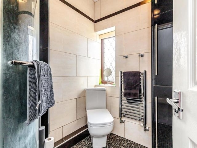 The first floor also houses this shower room, which consists of a white three-piece suite with chrome fittings. There's a tiled shower enclosure, a pedestal wash hand basin, with fitted mirror above, and a corner low-flush WC. A large, fitted storage cupboard is home for the gas-fired central-heating boiler.
