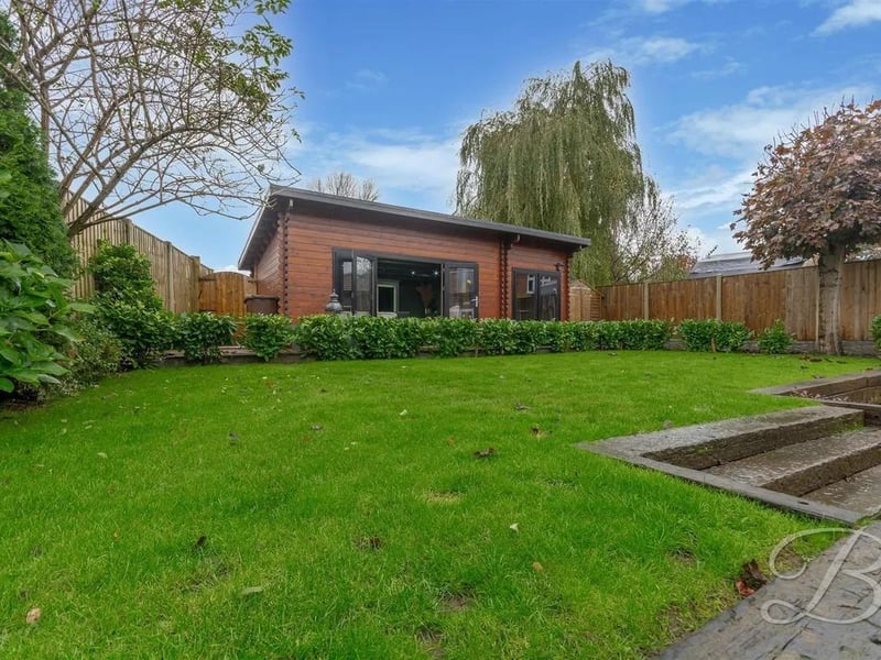 Featuring a beautifully maintained and enclosed garden to the rear with a spacious patio seating area and steps leading up to a lawn with surrounding mature shrubs and trees.