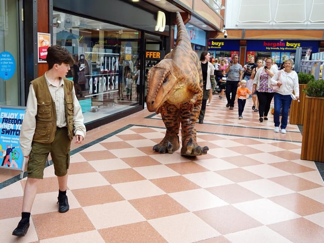 Crowds follow a dinosaur around the centre.