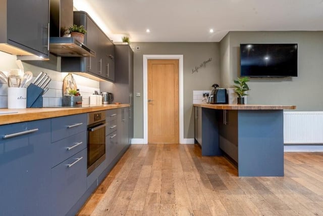 A wooden-topped breakfast bar, with matching units under, is a feature of the large kitchen. Integrated appliances include a dishwasher and fridge freezer, while an inset sink has a drainer and chrome mixer tap.