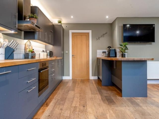 A wooden-topped breakfast bar, with matching units under, is a feature of the large kitchen. Integrated appliances include a dishwasher and fridge freezer, while an inset sink has a drainer and chrome mixer tap.