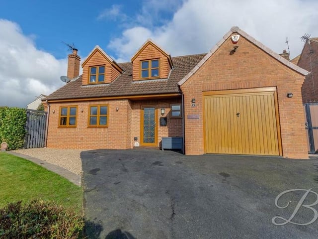 Let's step outside now, returning first to the eyecatching front of the £330,000-plus property, where a gated entrance opens on to a tarmac driveway, offering plenty of space for off-street parking. The driveway also leads to an impressive, integral garage, and sits next to a maintained lawn, with mature hedges..