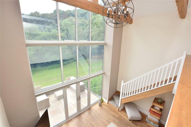 The huge barn windows in the living room help provide wonderful views out onto the property’s gardens and the woodland beyond, and also feature electric blinds to provide privacy.