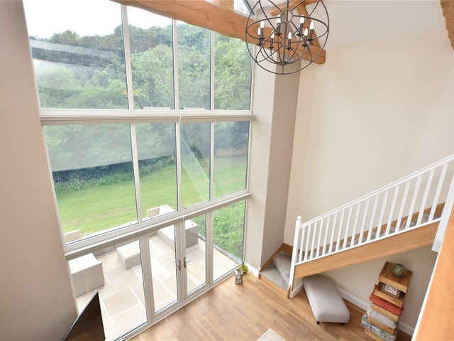 The huge barn windows in the living room help provide wonderful views out onto the property’s gardens and the woodland beyond, and also feature electric blinds to provide privacy.