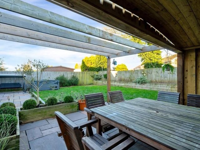 Check out the view from inside the partly-covered seating area within the wooden pergola in the back garden.