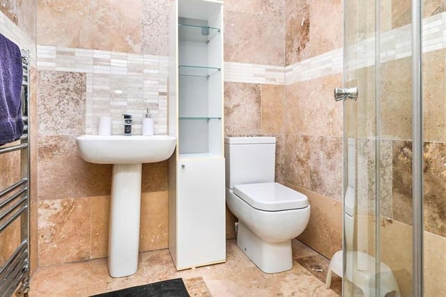 Here is one of the modern en suite rooms to the bedrooms on the second floor. It has a corner shower, low-flush WC and a wash hand basin, with tiled floor and walls.