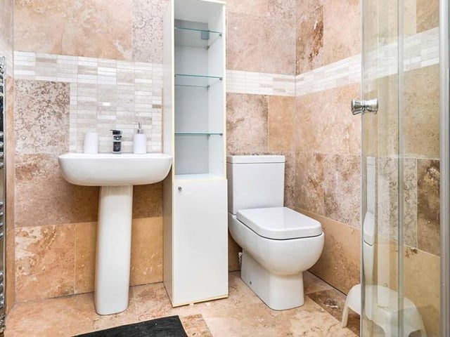 Here is one of the modern en suite rooms to the bedrooms on the second floor. It has a corner shower, low-flush WC and a wash hand basin, with tiled floor and walls.