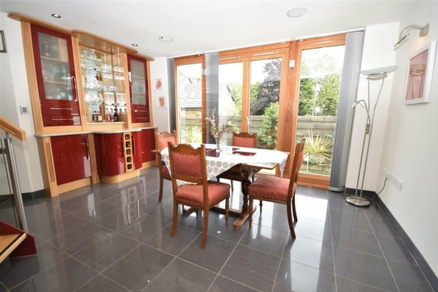 The dining room contains a bespoke, fitted bar area with display cabinets, adding to the notion that this is the ideal spot to entertain family and friends. Double doors open out to the garden.