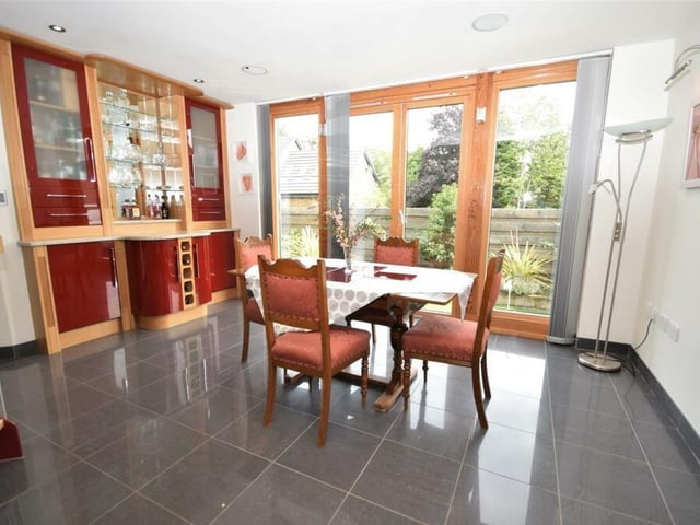 The dining room contains a bespoke, fitted bar area with display cabinets, adding to the notion that this is the ideal spot to entertain family and friends. Double doors open out to the garden.