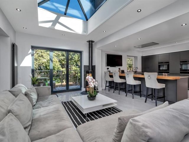 Another view of the bright and impressive open-plan living kitchen, with the breakfast bar that has a raised butcher's block work surface and also space for stools.