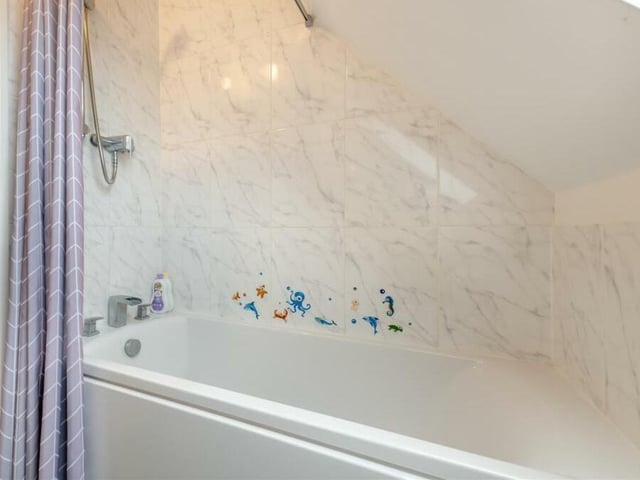 Here is the panelled bath, with mixer tap and shower over, within the family bathroom on the second floor.
