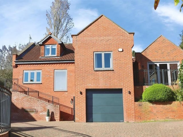 To the front, there is a large driveway with space for multiple vehicles and an internal garage.