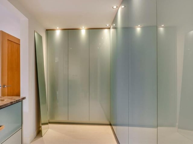 Part of the master bedroom is this contemporary dressing room, fitted with high-end Zurfiz wardrobes that have double hanging-rails, shelves, inset LED lighting and push-open doors. There is a separate 'soft close' drawer unit with marble worktop and fitted open shelving with mirror unit above.