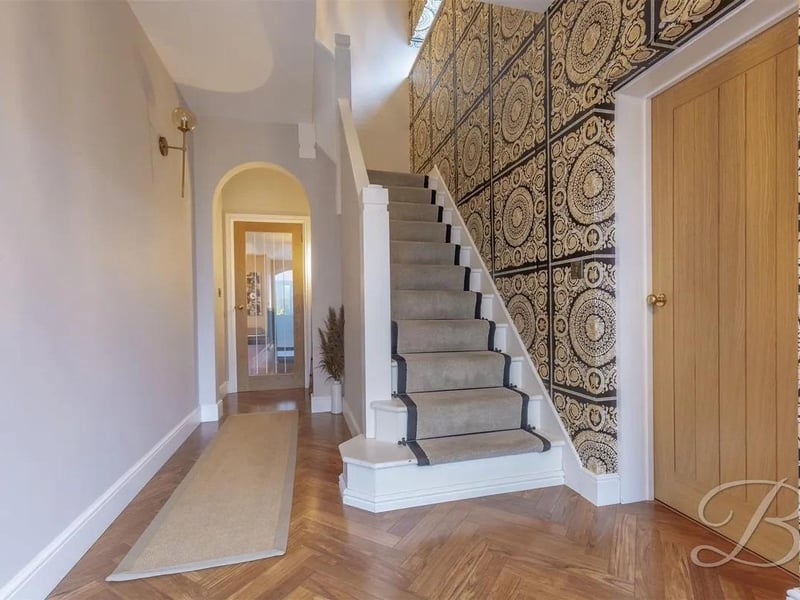 A warm welcome awaits as you step through into the entrance hall with parquet flooring, underfloor heating, stairs leading up to the first floor, and access into the living room