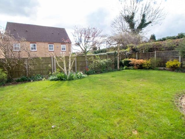 The back garden at the Sutton property is an ideal space for relaxation or play. Its borders contain plants and shrubs.