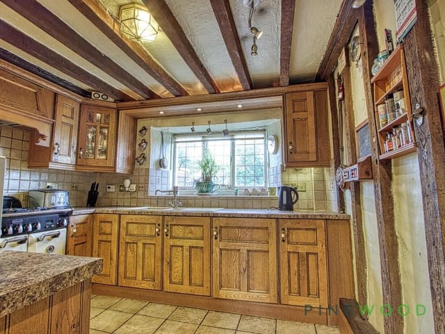 The kitchen is presented with traditional units and space for a range cooker set into a tiled alcove surrounded by solid wood door and drawer fronts