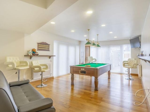 Another reception room at the bungalow is currently being used as a games room, with oak flooring and two sets of French doors providing easy access to the decking area and garden. But it is fitted with electric points in the event of a conversion into a fourth bedroom