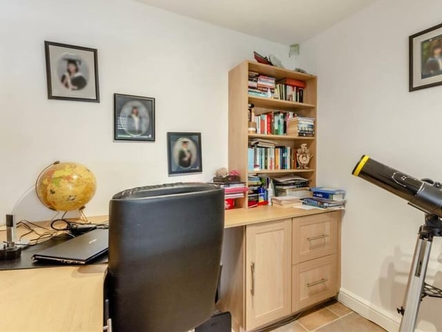 This compact study has an L-shaped fitted desk, cupboards, drawers and book shelves. The floor is tiled and has underfloor heating.
