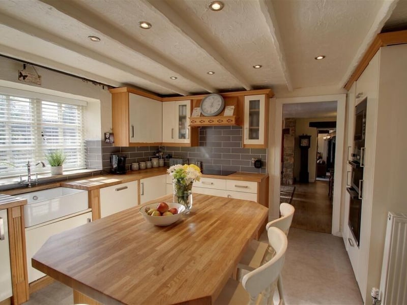 Let's begin our tour of the Whitwell farmhouse in this beautiful kitchen, with a central island unit that incorporates a breakfast bar with draws beneath. It is fitted with a classic range of wall and base units, complemented by an oak worktop that features a double drainer and Belfast sink.