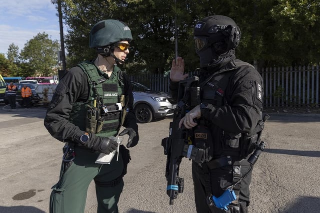 An armed police officer talks to a member of East Midlands Ambulance Service.