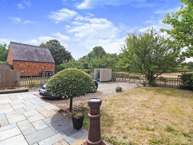 The front garden is a delightful mix of lawn, trees, hedgerow and paved patio area.