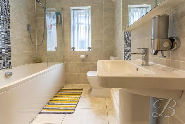 The family bathroom on the first floor features a panelled bath with screen and overhead shower, a low-flush WC and a wash hand basin. The window overlooks the side of the house.