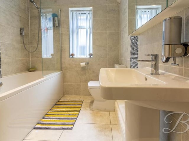 The family bathroom on the first floor features a panelled bath with screen and overhead shower, a low-flush WC and a wash hand basin. The window overlooks the side of the house.