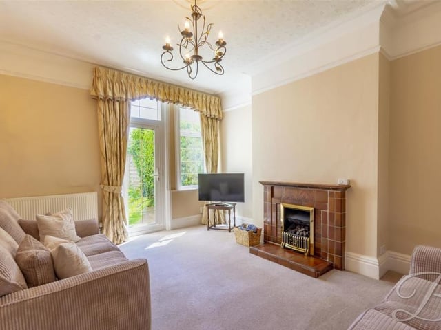 A second shot of the lounge shows its feature fireplace with surround. The room comes complete with a carpeted floor, central heating radiator and double-glazed window.
