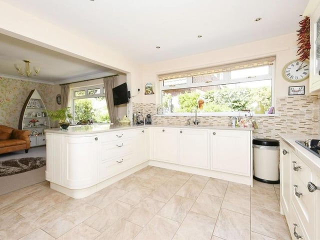 Another shot of the kitchen, with the dining area in the background. A host of integrated appliances include an electric oven, gas hob, cooker hood extractor, dishwasher, washing machine and fridge/freezer. Down spotlights add a touch of class.