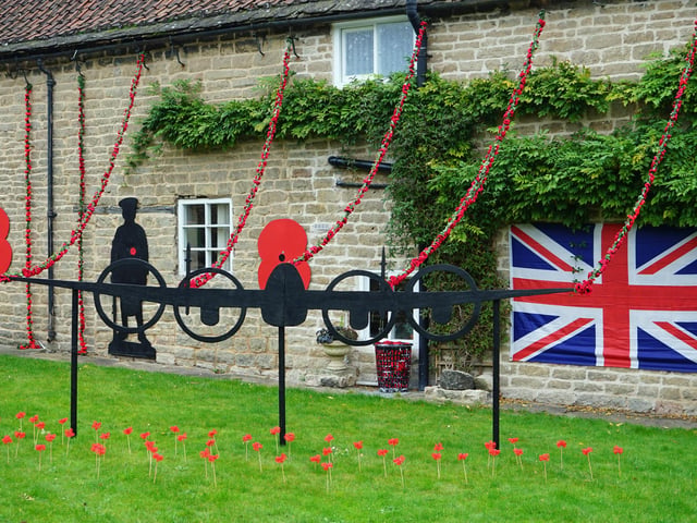 Cottages along the A60 proudly display poppies, flags, and soldiers in their gardens.