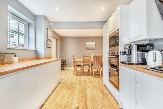 This photo shows how the kitchen leads through to a dining area. As well as the integrated appliances, there is space and plumbing for a washing machine and tumble dryer concealed behind the cabinets.