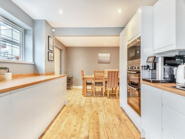 This photo shows how the kitchen leads through to a dining area. As well as the integrated appliances, there is space and plumbing for a washing machine and tumble dryer concealed behind the cabinets.