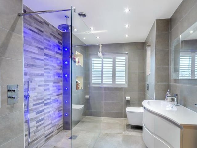 The en suite wet room to the master bedroom is terrific, especially its large walk-in shower enclosure with screen. A vanity unit with inset wash hand basin has two soft-closing drawers beneath and a fitted mirror above, while a wall-hung, low-flush WC has an enclosed cistern. The floor and walls boast beautiful porcelain tiles, and there are five recess/display areas with inset spotlights, plus nine ceiling LED spotlights.