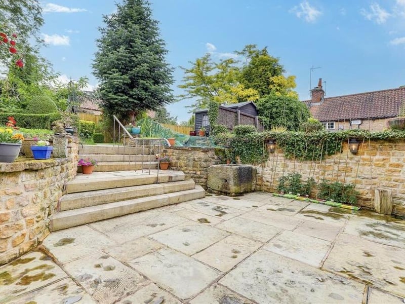 A paved flagstone patio, complete with steps leading up to a lush lawn, is one of the highlights of the rear garden.