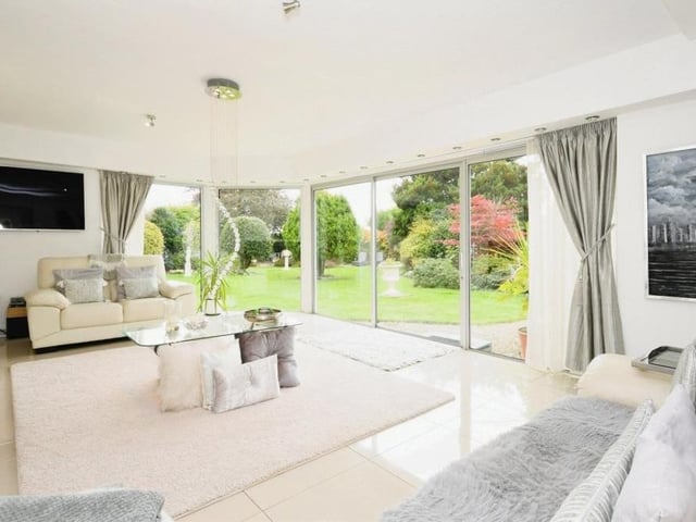 Let's move on now to the sumptuous sitting room, which is distinguished by its patio doors leading to the back garden and its floor-to-ceiling windows.