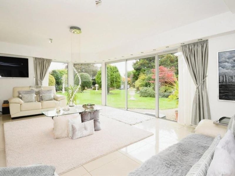 Let's move on now to the sumptuous sitting room, which is distinguished by its patio doors leading to the back garden and its floor-to-ceiling windows.