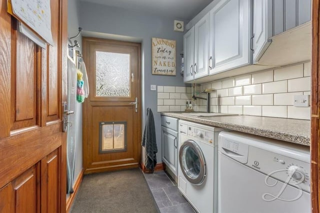 Just off the kitchen is this convenient utility room, which boasts plumbing for a washing machine, a work surface and inset sink with mixer tap above. There are also cabinets for additional storage, while the door leads outside.