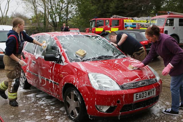 Firefighters and supporters get stuck in to the charity car wash.