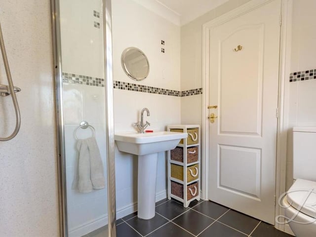 Here is another en suite bathroom to one of the first-floor bedrooms. It includes a walk-in shower cubicle, low-flush WC, hand wash basin and full-height tiling.