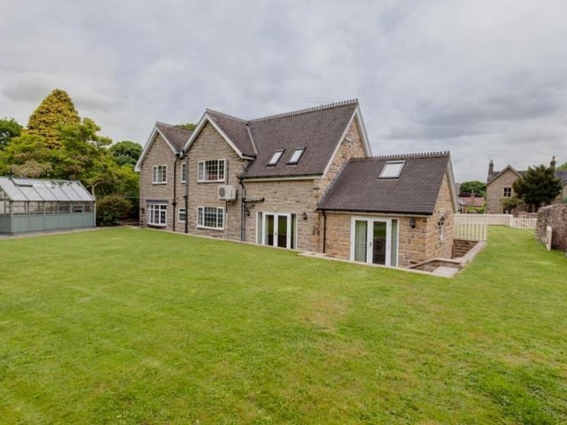 At the back, steps rise to a garden that is mainly laid to lawn but also has mature trees and shrubs. In one corner is a gravelled area with a greenhouse, and it is all enclosed by stone walling and fencing.