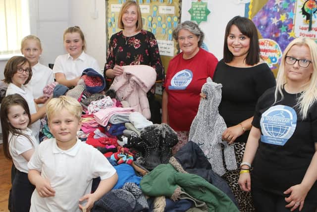 Forest Glade Primary pupils and teacher Thea Avison handing over clothes collected as part of their harvest festival to the Share Wear charity.