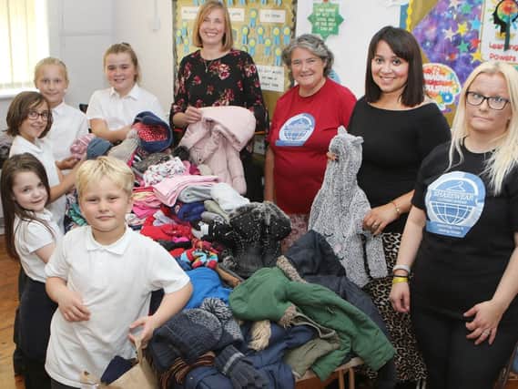 Forest Glade Primary pupils and teacher Thea Avison handing over clothes collected as part of their harvest festival to the Share Wear charity.