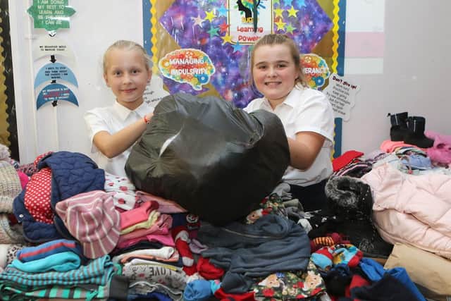 Brooke and Chloe with some of the mountain of clothes collected as part of the harvest festival at Forest Glade Primary