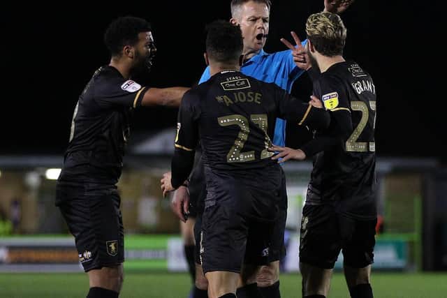 Mansfield players appeal to referee Christopher Sarginson for a penalty after Nicky Ajose and Jorge Grant are felled in quick succession.